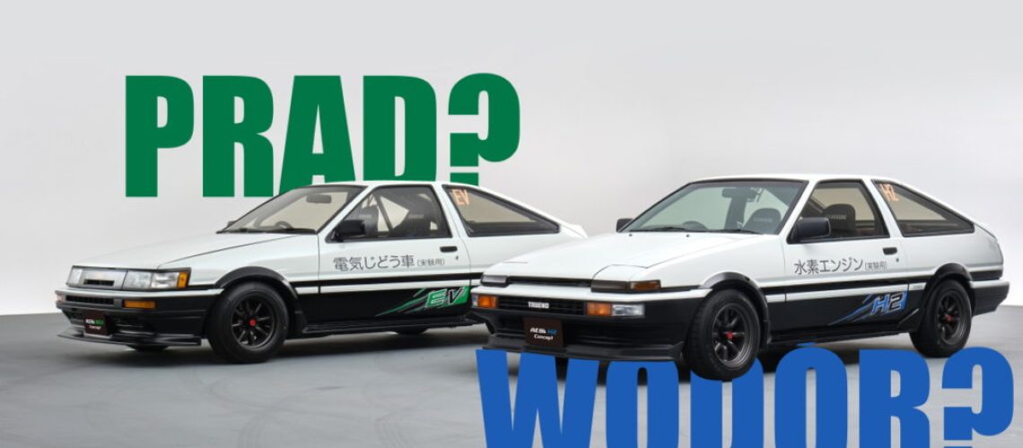 Dwie biało-czarne Toyoty AE86, jedna oznaczona "EV", nad którą znajduje się zielony napis "prąd?" oraz oznaczona H2 a pod nią niebieski napis "wodór: